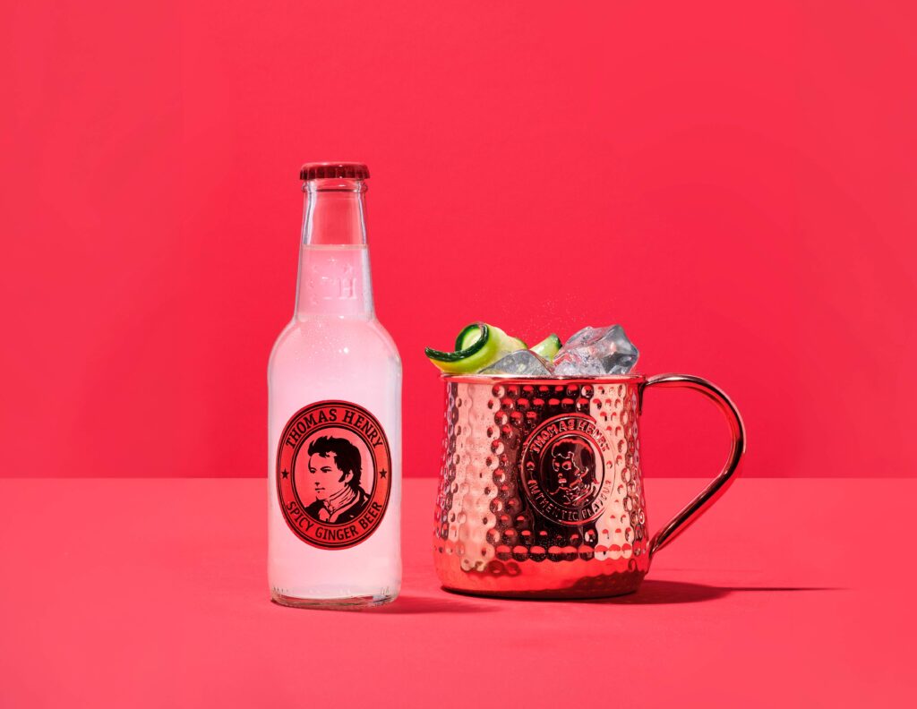 Thomas Henry Spicy Ginger mit 0,2l Glasflasche und Moscow Mule Drink im Kupferbecher daneben